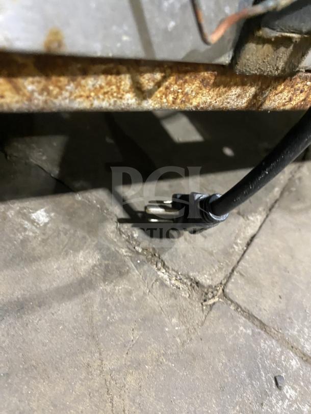 Rusted underside of a Continental salad/sandwich prep table with visible electrical plug. Surface wear indicated.