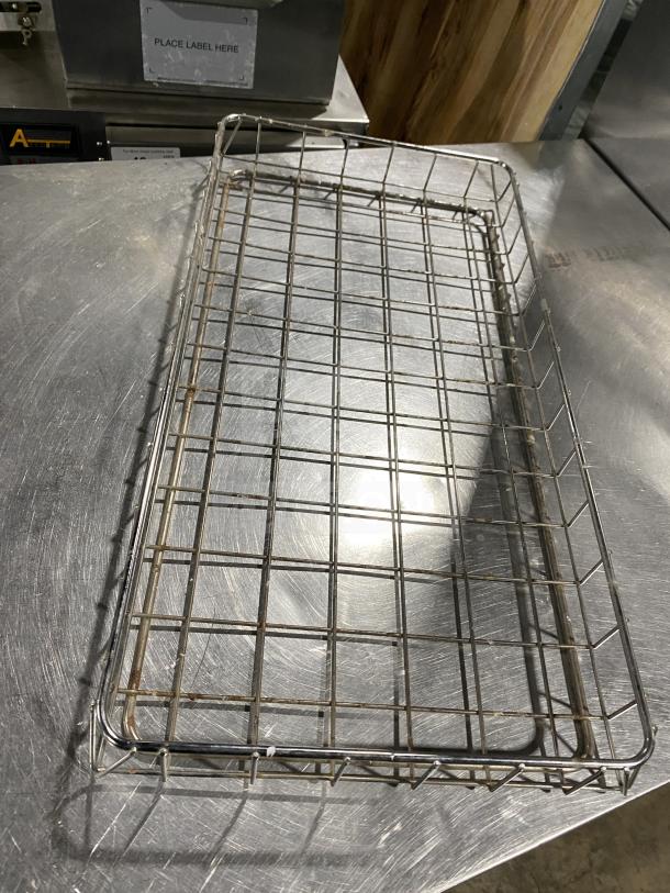 Stainless steel bagel rack in good condition, featuring a grid design for commercial use, with label space visible.