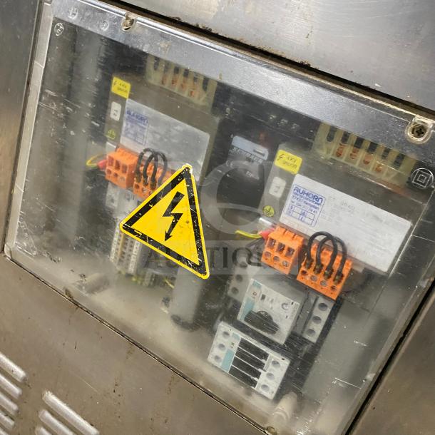 Stainless steel Multivac chamber vacuum packing machine, control panel with safety warning label, visible wiring details.