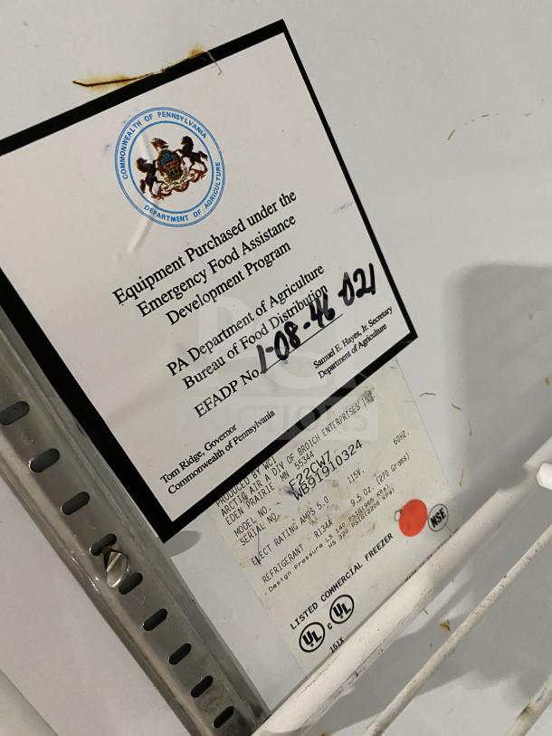 Arctic Air commercial freezer, model F22CW7, stainless steel, white finish, on casters, includes rack, with tags and labels visible.