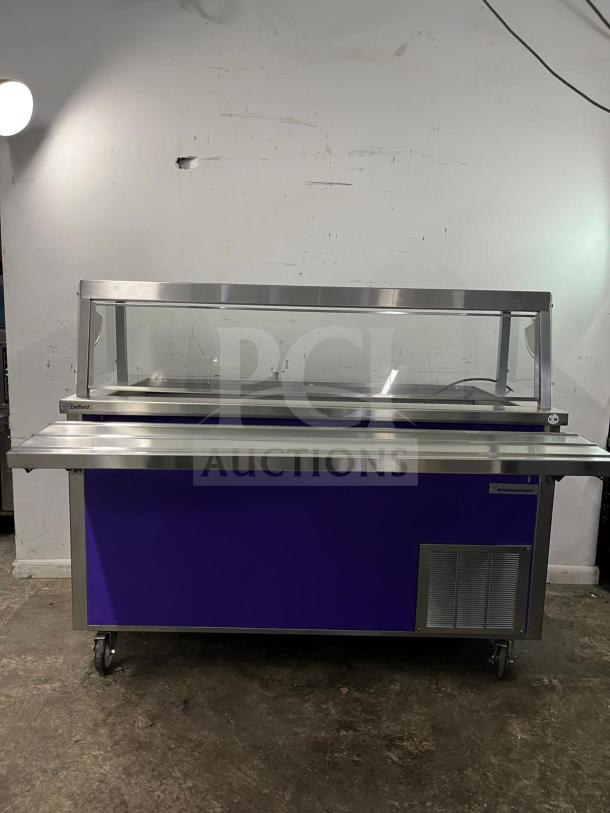 Brand new Delfield SCSC-60-EEP 60-inch refrigerated food prep table, stainless steel, purple panel, on wheels.