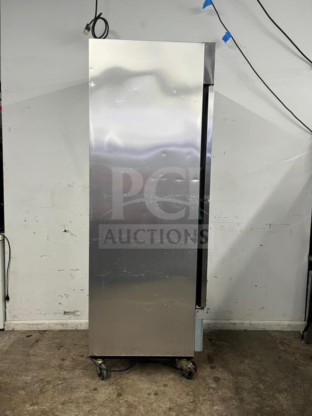 TRUE T-23-2 refrigerator with two left hinge solid doors, stainless steel finish, on caster wheels, 115V. Some surface wear visible.