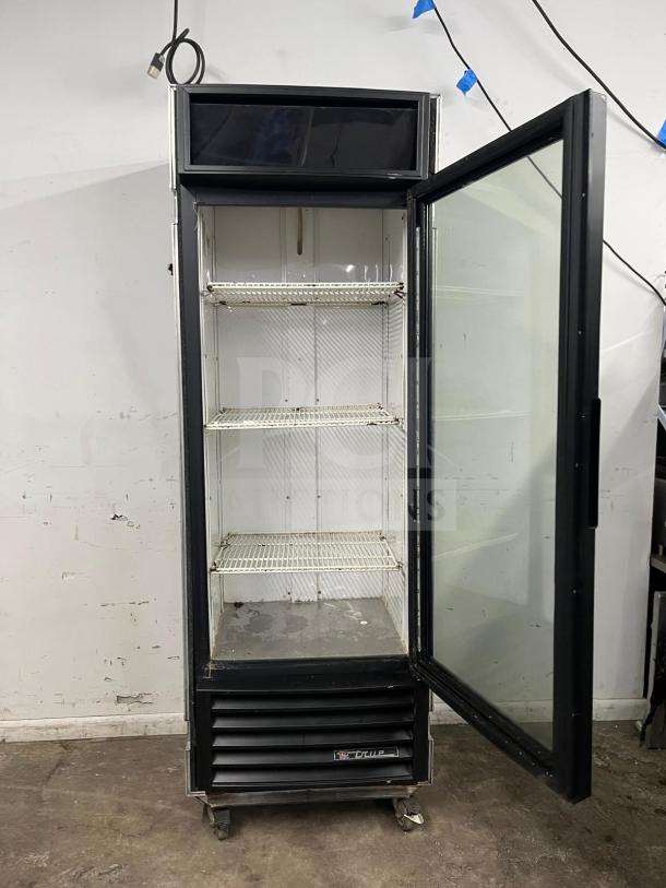 TRUE GDM-19T-LD black refrigerated glass door merchandiser, LED lighting, three shelves, visible wear, on casters.