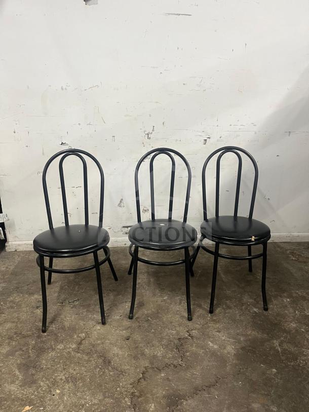 Three cafe dining chairs with black frames, padded vinyl seats. Minor wear visible. Perfect for a casual dining setting.