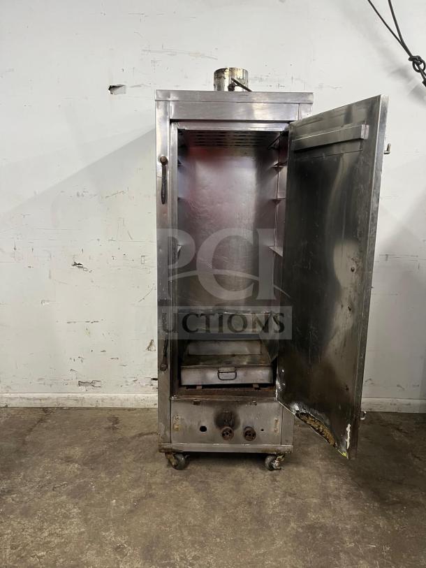 Universal smoker oven with galvanized interior, 3 burners, 78" tall. Metallic exterior, open door, on wheels, used condition.