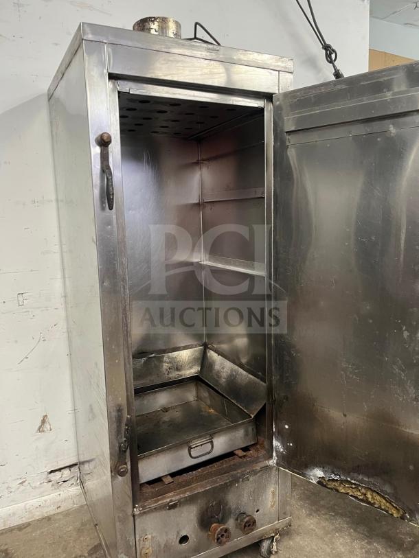 UNIVERSAL smoker oven, galvanized interior, 3 burners, 78" tall. Stainless steel with visible wear. Auction item for sale.