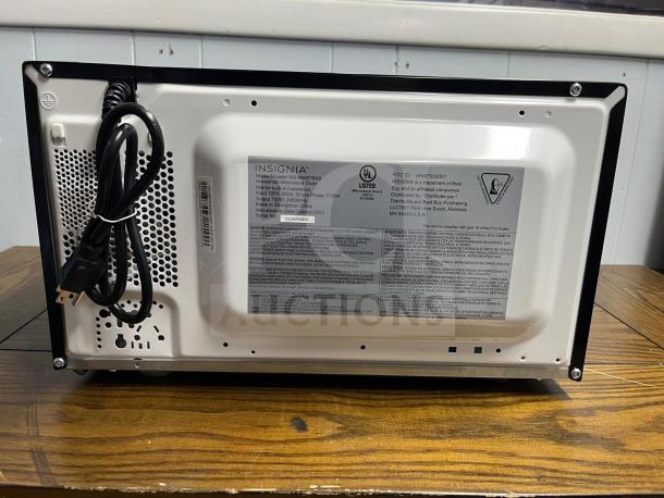 Insignia NS-MW07BKO-d compact countertop microwave, 0.7 cu. ft., black, back view showing labels and power cord.