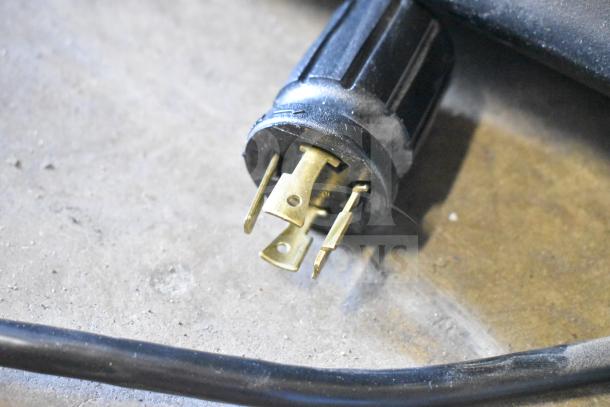 Close-up of a power plug for a 2016 True GDM-49F-HC Commercial Freezer, showing prongs and black casing on a concrete floor.