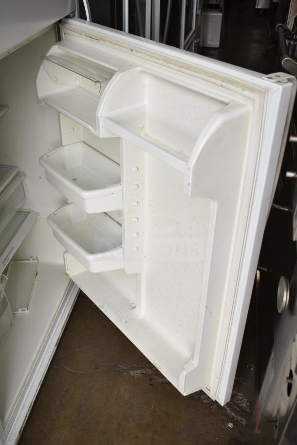 Whirlpool W1TXNMFWQ00 reach-in cooler with freezer, interior shelving, visible wear and stains, suited for commercial use.