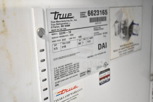 True GDM-12 cooler label detailing model, serial number 6623165, 115 volts, 1 phase, with 2-year lamp warranty.