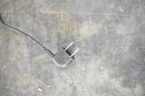 Alt text: Close-up of a plug on a textured surface, related to auction of 2 Samsung UN55NU6900B 55" TVs.