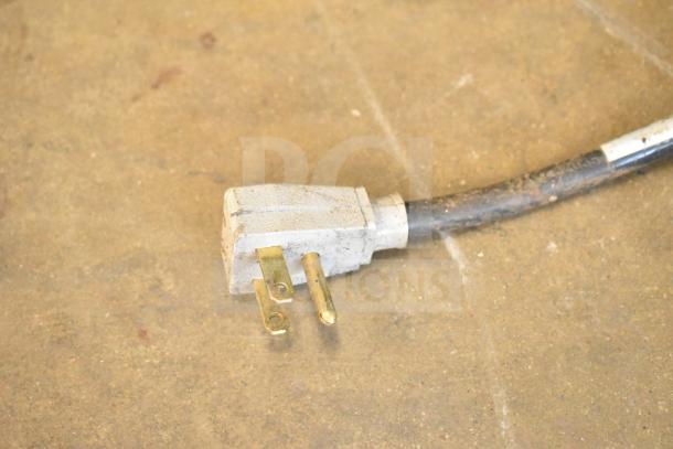 Close-up of a plug for a True GDM-49-HC cooler. Signs of use are visible on the plug and cable.