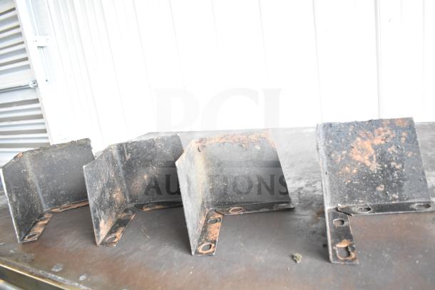 Rusty metal brackets on a surface, possibly used for support or mounting. Weathered condition.