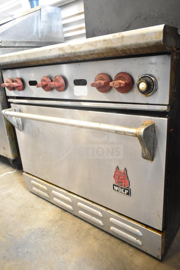 Wolf CHSSR-6-29 commercial gas range with 6 burners, oven, and backsplash. Visible wear. Wolf logo on lower panel.