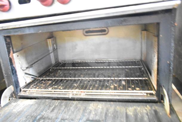 Wolf CHSSR-6-29 commercial gas range with 6 burners, oven, and backsplash. Visible wear. Oven interior and knobs shown.