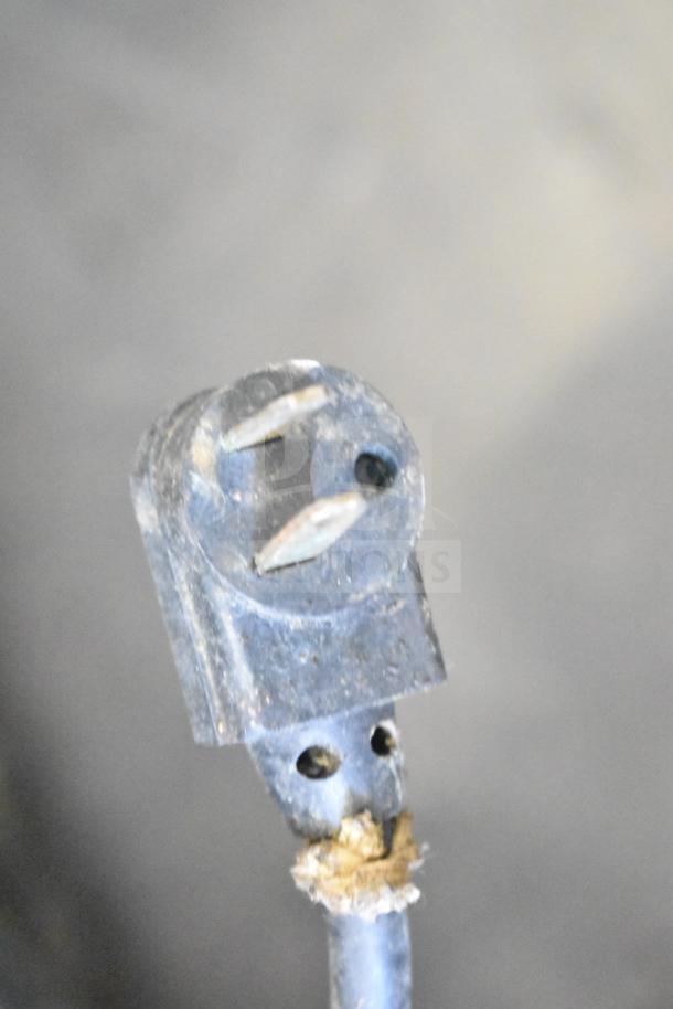 Close-up of a worn two-prong electrical plug; visible fraying at the wire connection.