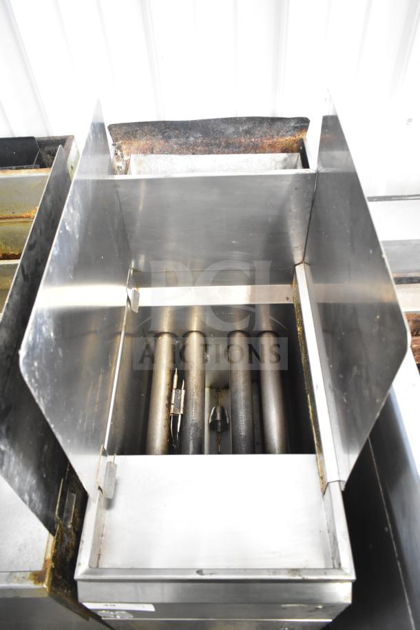 Commercial gas-powered deep fat fryer, stainless steel, open top view showing burner tubes, used condition, signs of wear.