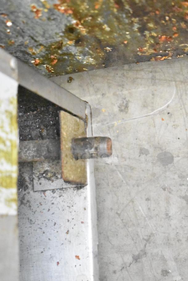 Commercial gas-powered deep fat fryer, shown with signs of use and residue, indicating active operation.