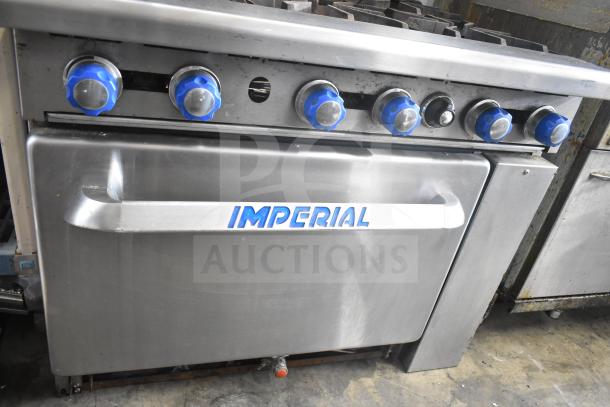 Imperial commercial gas range with 6 burners, oven, over shelf, and backsplash. Features blue control knobs.