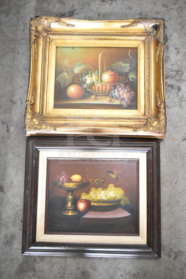 Two framed still life paintings of fruit in ornate gold and dark wood frames. Top frame shows damage in one corner.