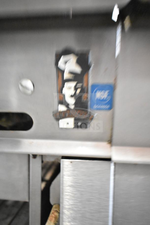 Montague UF-36R commercial gas range, featuring 6 burners, left side charbroiler, undershelves, and mounted on casters.