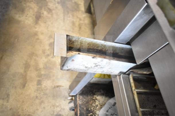 Montague UF-36R gas range, 6 burners, left-side charbroiler, under shelves, commercial casters; visible wear on metal surface.