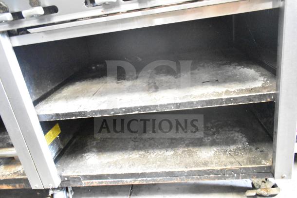 Montague UF-36R commercial range under shelves with visible wear, mounted on commercial casters.