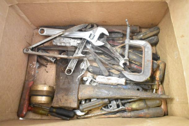 Box of assorted tools and hardware, including wrenches, a C-clamp, and screwdrivers, showing signs of wear.
