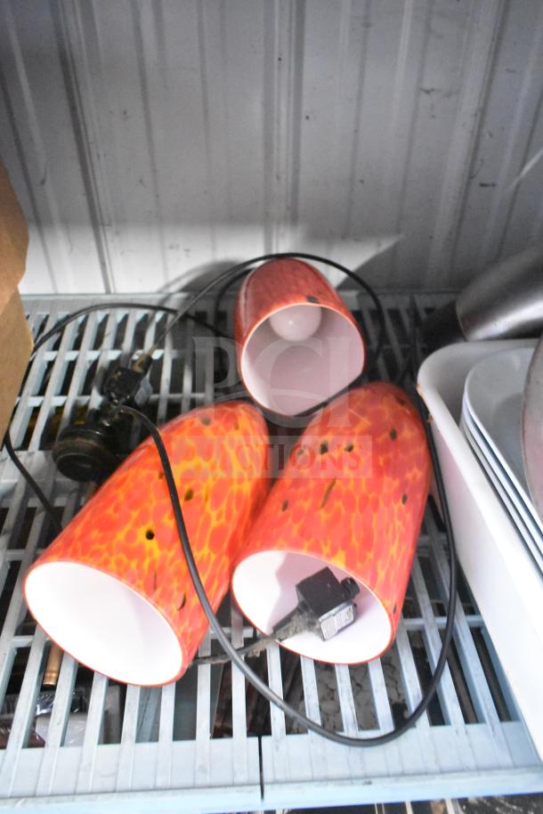 Lot including red-orange pendant light covers with cords, placed on a metal shelf. Additional items include trays and tools.