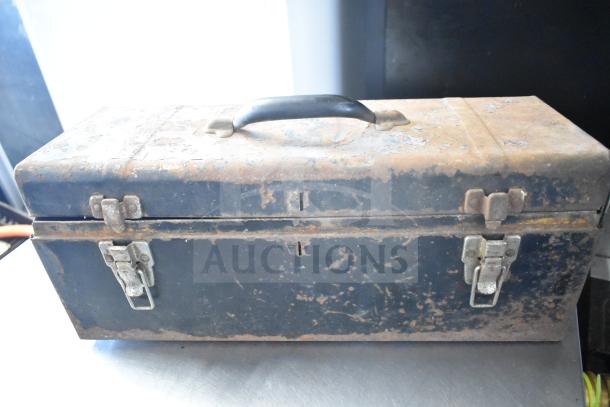 Rustic metal toolbox with handle and latches, showing signs of age and wear, part of a mixed tool auction lot.
