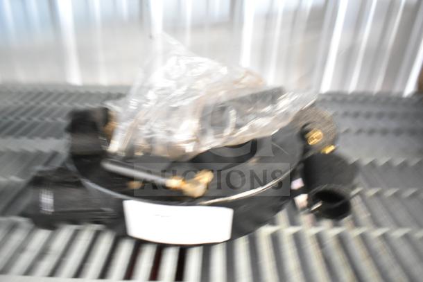 Blurry image of a ring burner for a range, featuring black metal components and brass fittings. Condition unclear.