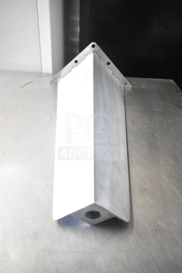 A triangular metal leg with mounting holes, brand new, placed on a metallic surface.