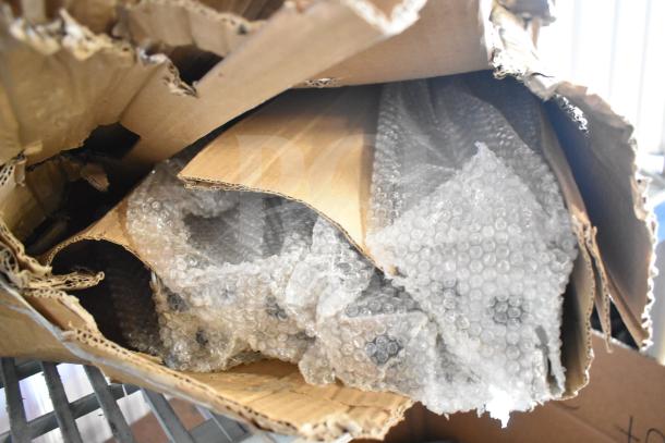 A damaged cardboard box containing brand new legs wrapped in bubble wrap, indicating unused condition.