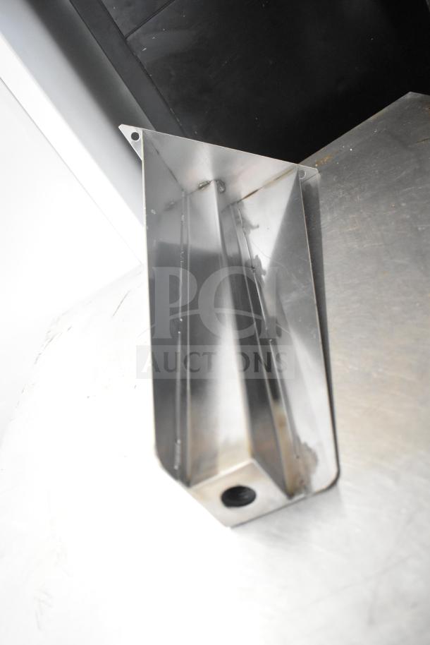 Metal component with angular design, possibly a bracket or leg support, in new condition. No visible labels or markings.