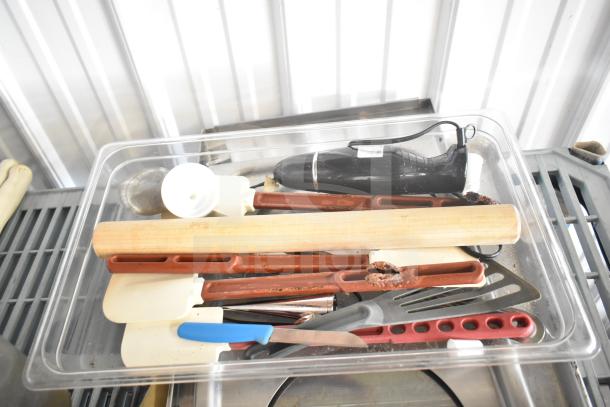 Lot of kitchen items in plastic bin including utensils, rolling pin, spatulas, and a mixing tool. Mixed condition.
