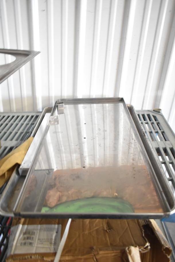 Assorted kitchen items including stainless steel drop-in bins, a cutting board, and round baking sheets. Visible wear.