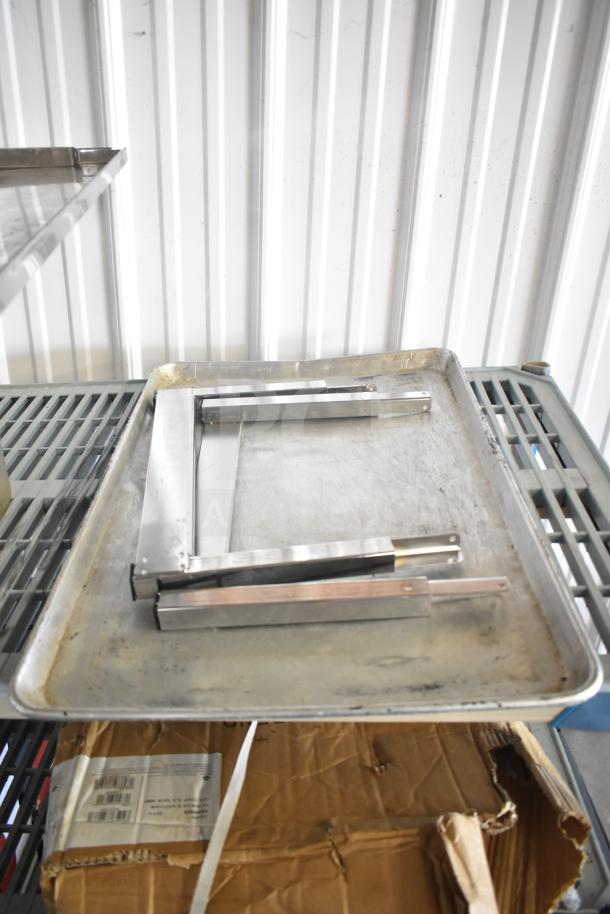 Lot of various kitchen items including stainless steel drop-in bins, baking sheets, and utensils on a metal rack, used condition.