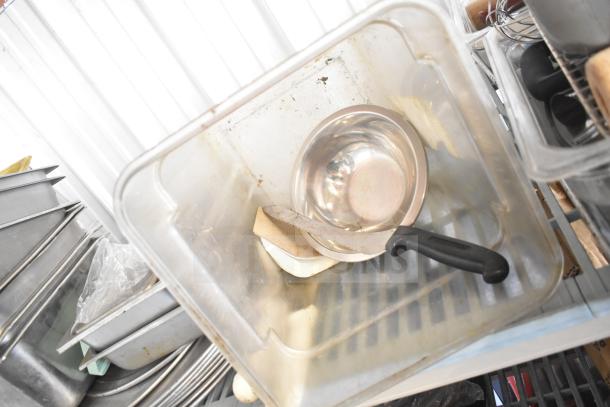 Assorted kitchen items including a stainless steel bowl, cutting board, and knife in a drop-in bin. Used condition.