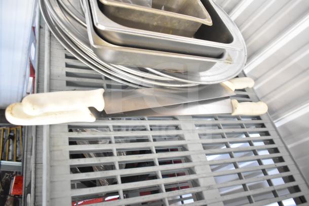 Lot of kitchen items including stainless steel drop-in bins, round baking sheets, knives, and utensils.