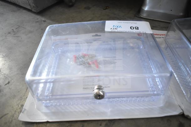 Clear thermostat guard with screws; includes packaging and item label indicating Honeywell Home CG512A model.