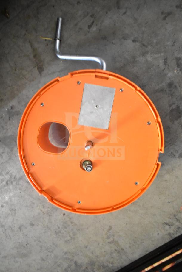 Orange countertop vegetable cutter with manual crank handle, showing top view. Appears in good condition.