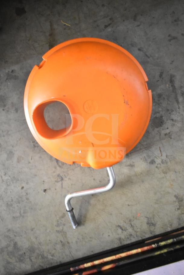 Orange countertop vegetable cutter with hand crank, scratches on surface, circular design. Ideal for efficient chopping.