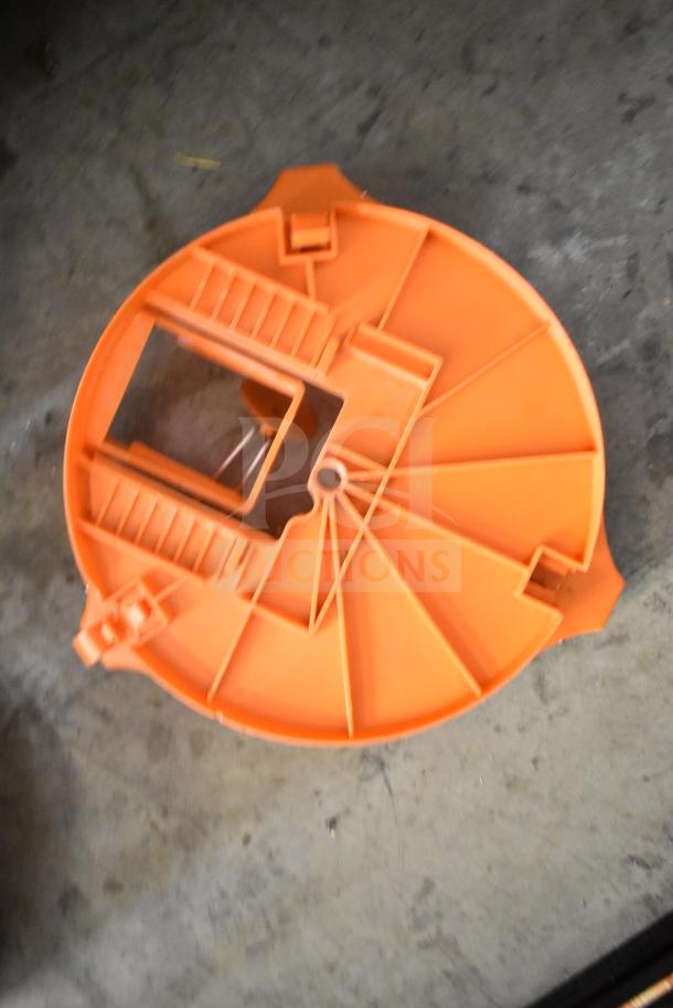 Orange countertop vegetable cutter, circular design, good condition, includes compartments and blade slot for slicing.