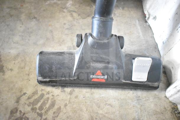Bissell 4122 Zing Vacuum Cleaner, black, showing nozzle with red logo. Condition appears used with some dust.