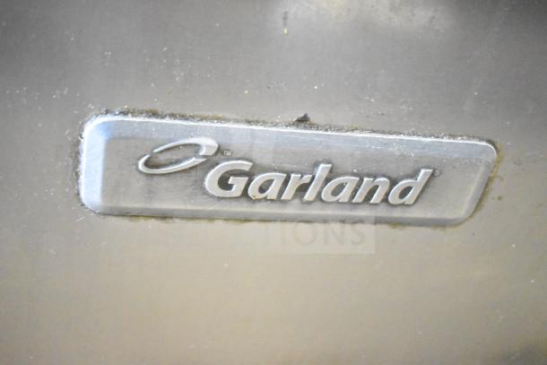 "Garland logo on commercial 6 burner range with oven, over shelf, and backsplash, showcasing brand authenticity."