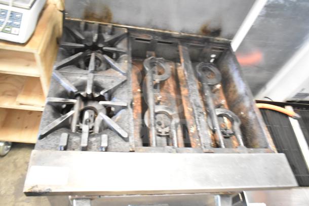Garland Commercial 6 Burner Range with oven, featuring overshelf and backsplash. Shows signs of use, sturdy condition.