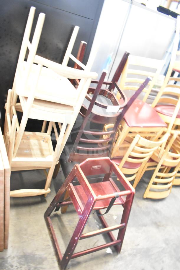 Stacked wooden and metal chairs, including a high chair and dining chairs, in good condition. Auction lot of seven items.