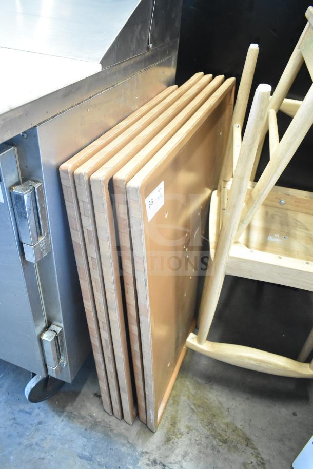 Five stacked wooden tabletops, square shape, light finish, in good condition. Label with lot number visible.