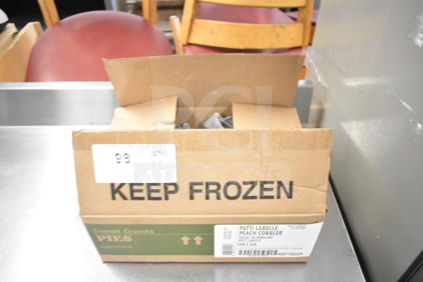 Cardboard box labeled "Keep Frozen" and "Sweet Goods Pies," contains items. Tags indicate quantity and type. Contents unspecified.