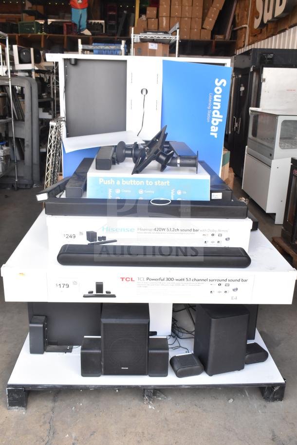 Speaker store display with Samsung, LG, Bose, Hisense, TCL, Vizio sound bars; price tags visible; various models arranged.